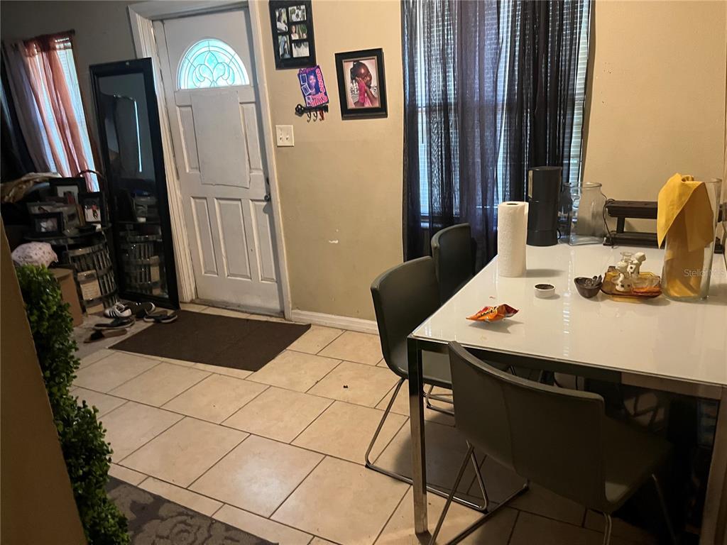 A dining area features a white table, four gray chairs, tiled flooring, and an entryway door — 3104 E CHELSEA STREET, TAMPA, FL
