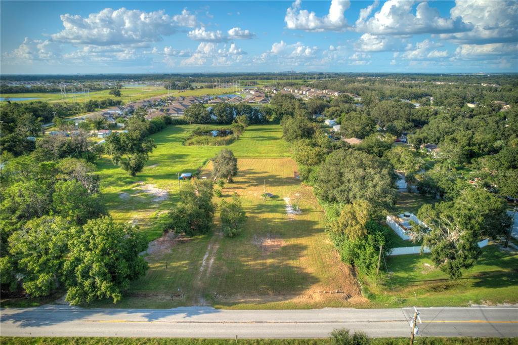 An aerial view shows a rectangular, grassy vacant lot bordered by trees and a road — 1520 21ST AVENUE SE, RUSKIN, FL