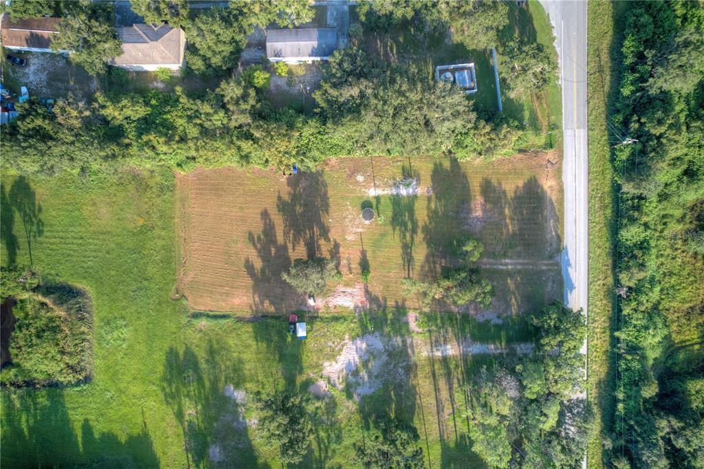 An aerial view shows a rectangular, partially cleared lot bordered by trees and a road — 1520 21ST AVENUE SE, RUSKIN, FL