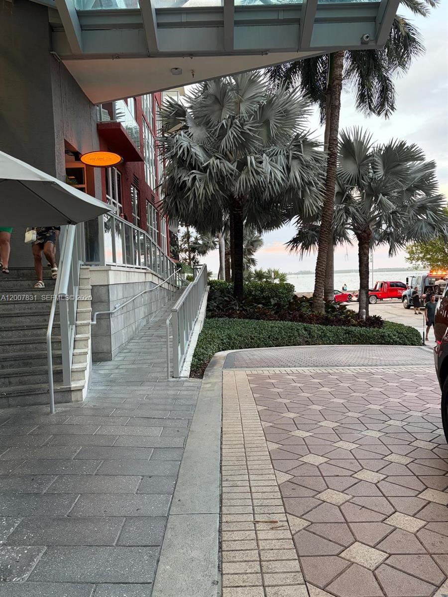 An outdoor walkway with stairs and a ramp leads toward a building entrance near palm trees — 1155 Brickell Bay Dr # 1201, Miami FL 33131, MIAMI, FL