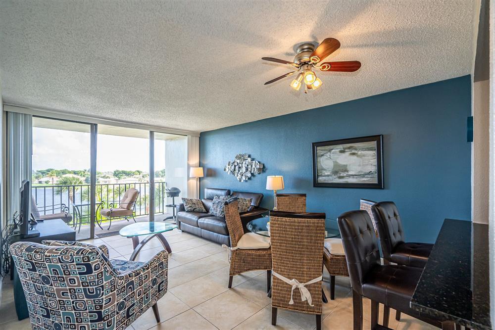 A living and dining area features tile floors, a blue accent wall, and a balcony — 1830 Embassy Drive # 409, West Palm Beach FL 33401, WEST PALM BEACH, FL