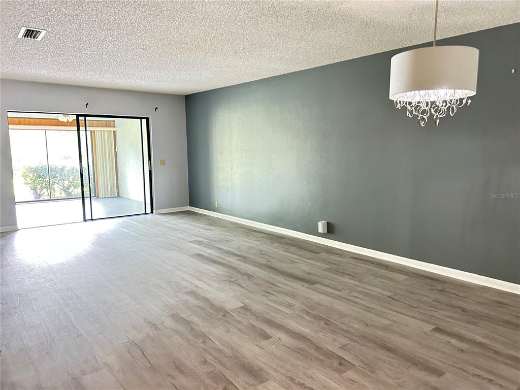 A living room features gray wood-look flooring, a dark accent wall, and a drum chandelier — 1026 MEDINAH DRIVE, WINTER HAVEN, FL