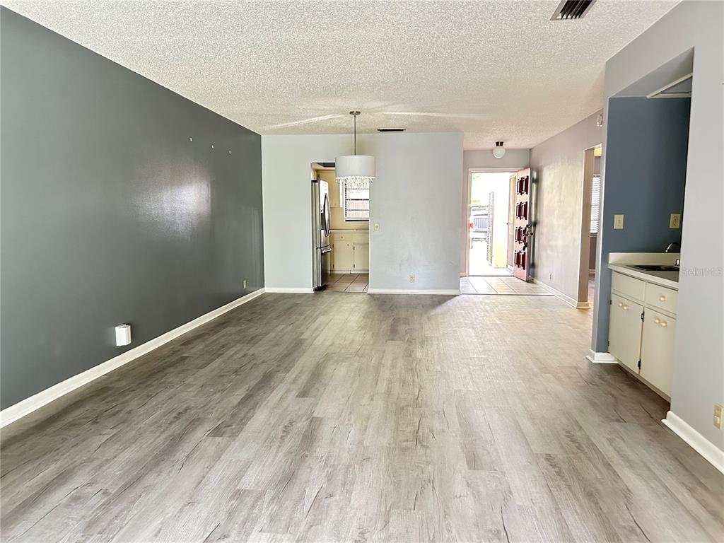 An open-concept living area features gray wood-look flooring, a dark accent wall, and a kitchen — 1026 MEDINAH DRIVE, WINTER HAVEN, FL