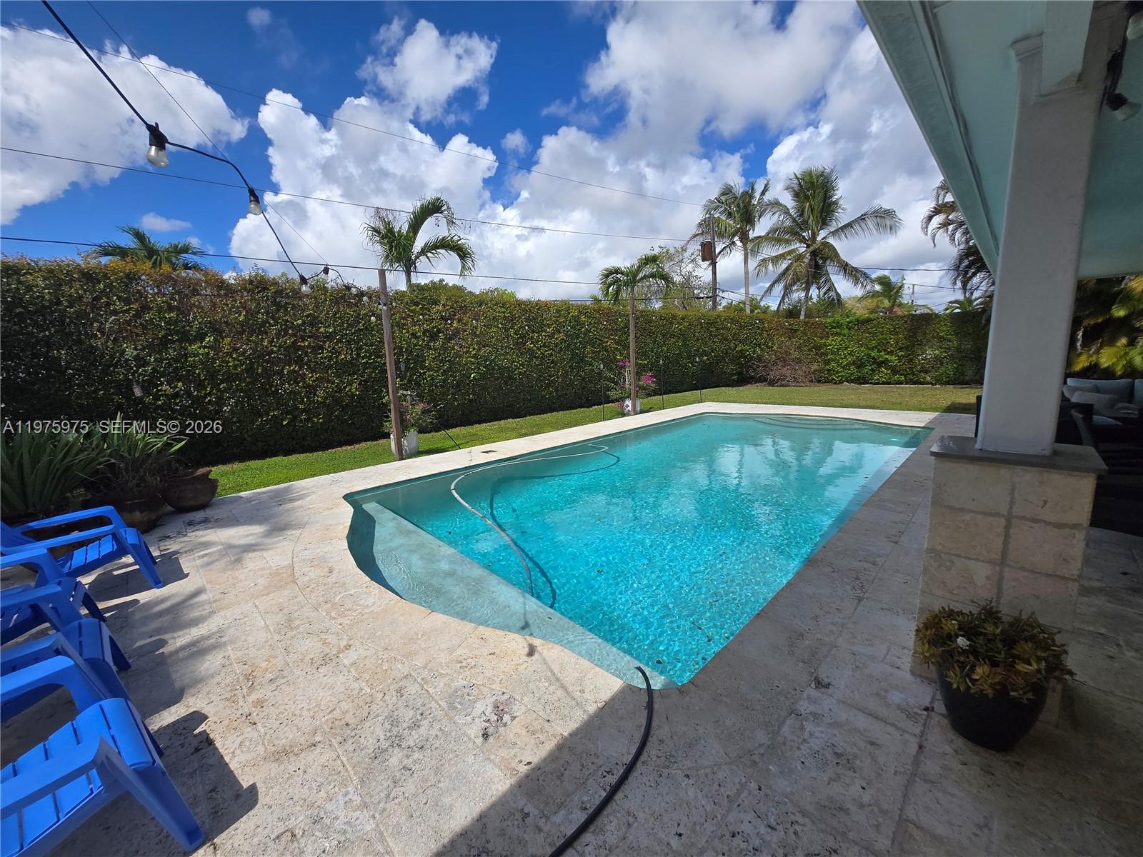 A rectangular swimming pool sits on a stone patio next to a manicured hedge — 8620 SW 85th Ave, Miami FL 33143, MIAMI, FL