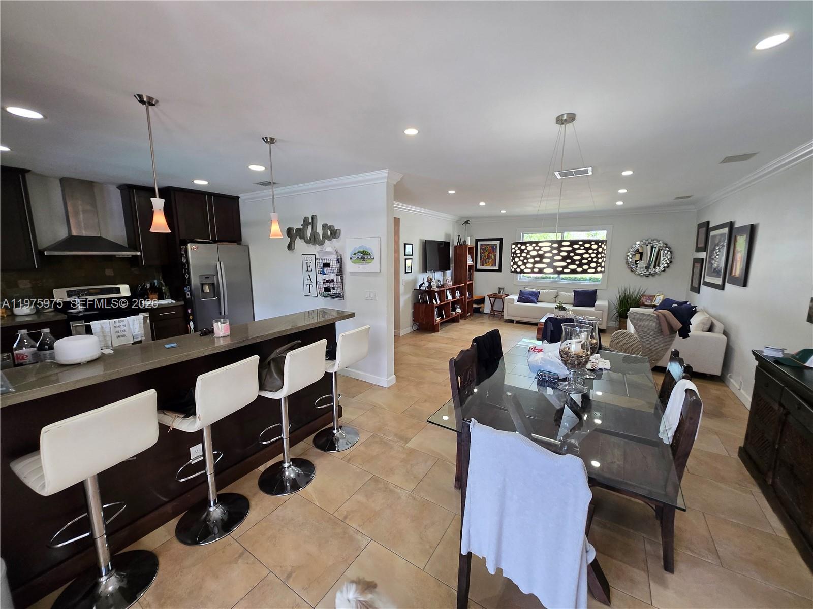 An open-concept kitchen with a breakfast bar flows into a dining area and living room — 8620 SW 85th Ave, Miami FL 33143, MIAMI, FL