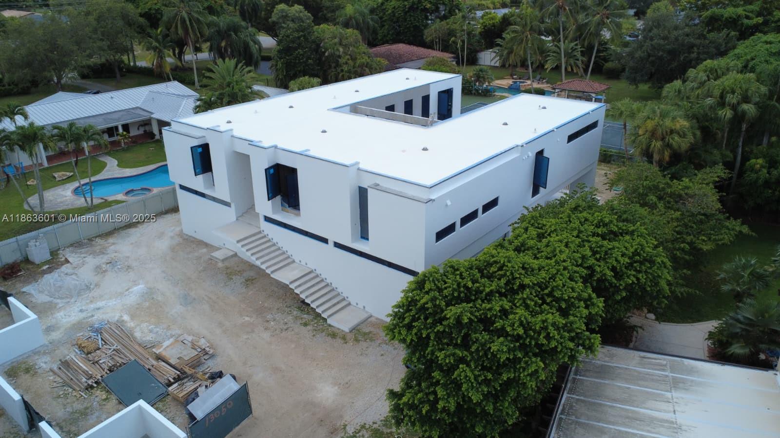 An aerial view shows a modern, white, U-shaped house under construction with a flat roof — 13050 SW 103 Ave, Miami FL 33176, MIAMI, FL