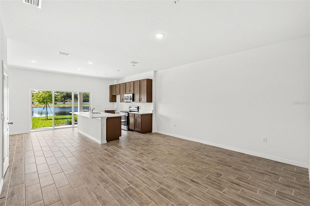 An open-concept kitchen and living area features wood-look tile flooring and sliding glass doors — 4905 WINDING RIVER ROAD, ORLANDO, FL