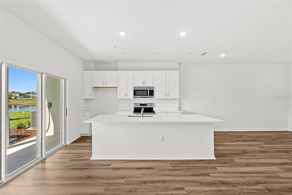 A kitchen with white cabinets, a central island, and a sliding glass door to outdoors — 4905 WINDING RIVER ROAD, ORLANDO, FL
