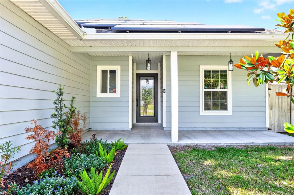 A light gray house exterior features a front porch, a glass-paneled door, and solar panels — 116 W 5TH STREET, CHULUOTA, FL