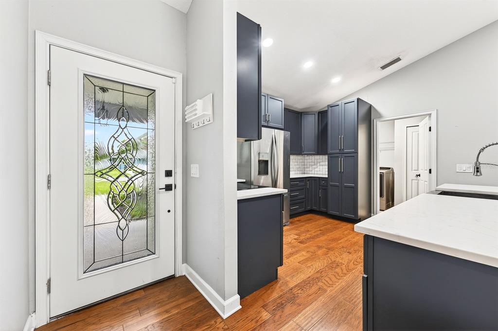 A kitchen with dark blue cabinets and wood flooring sits next to a front door — 116 W 5TH STREET, CHULUOTA, FL