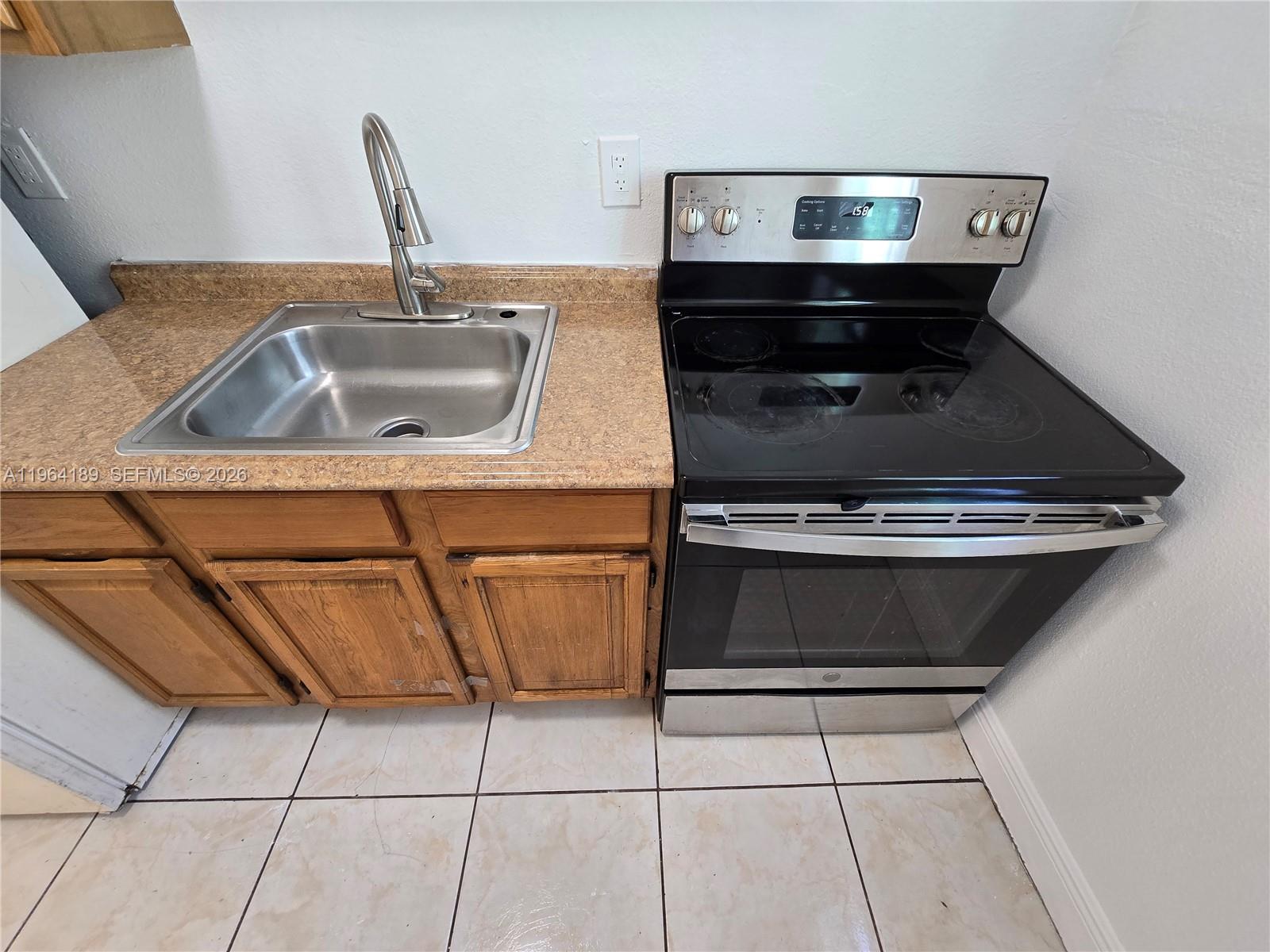 A kitchen features a stainless steel sink, a black electric stove, and wood cabinets — 535 NW 7th St # 9, Miami FL 33136, MIAMI, FL