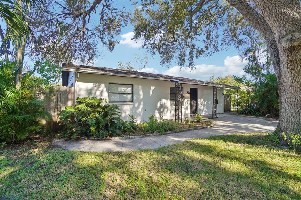 A single-story house with a white brick exterior, a concrete driveway, and large shade trees — 162 SE LINCOLN CIRCLE N, ST PETERSBURG, FL