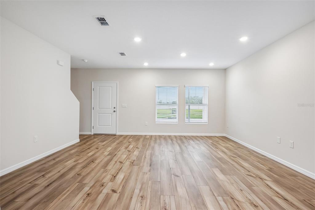 An empty room with light-colored walls, wood-look flooring, recessed lighting, and two windows — 9176 BENT BRANCH, DADE CITY, FL