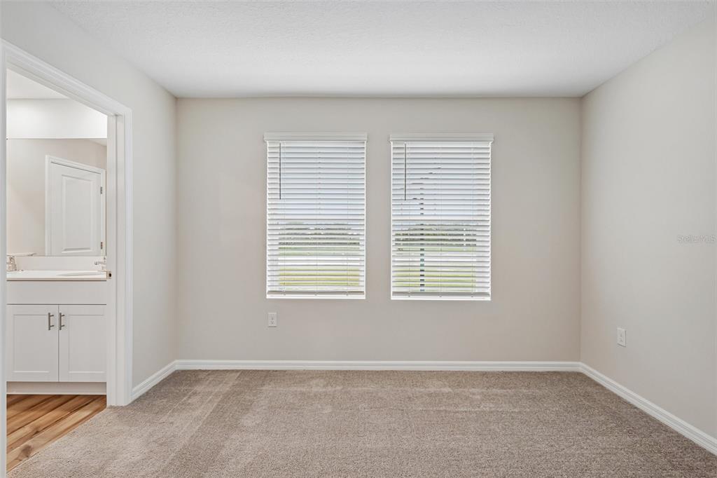 An empty bedroom with beige carpet, light walls, and two windows with white blinds — 9176 BENT BRANCH, DADE CITY, FL