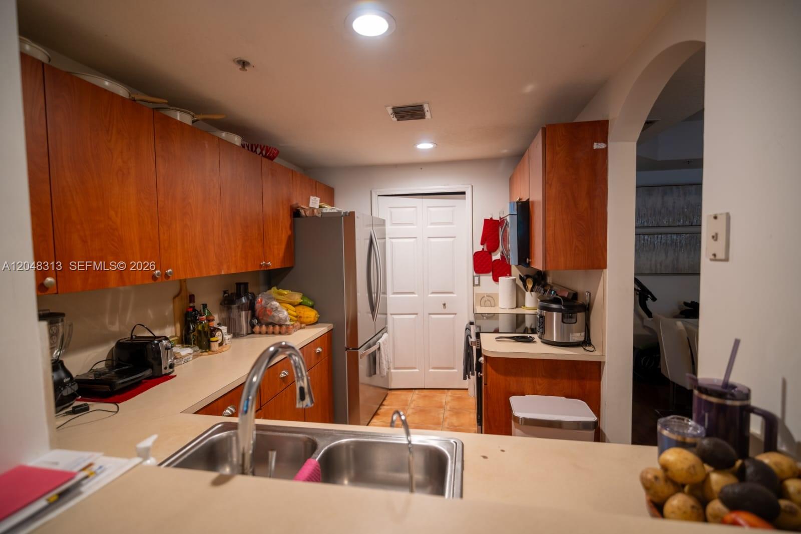 A kitchen features wood cabinets, stainless steel appliances, a double sink, and light-colored countertops — 6520 NW 114th Ave # 1626, Doral FL 33178, DORAL, FL