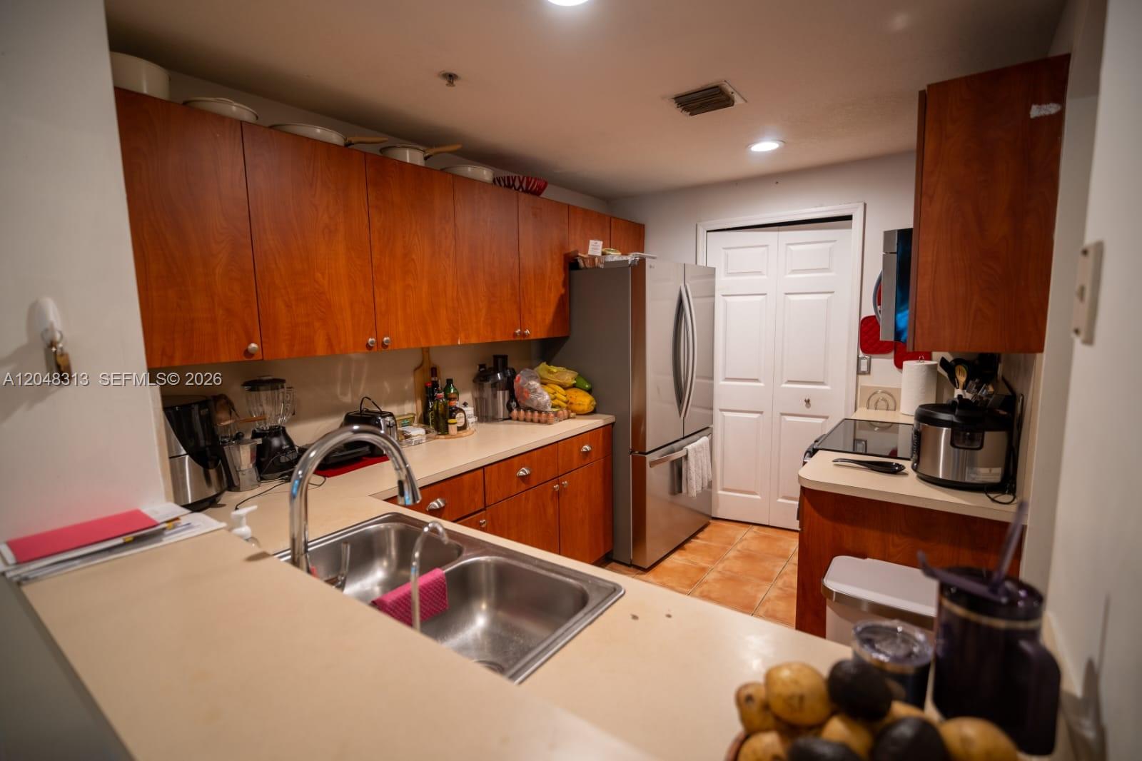 A kitchen features wood cabinets, stainless steel appliances, a double sink, and beige countertops — 6520 NW 114th Ave # 1626, Doral FL 33178, DORAL, FL
