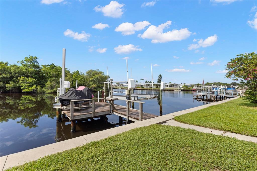 A wooden boat dock with a covered jet ski sits along a canal with grass — 436 MOUNT OAK AVENUE NE UNIT 747, ST PETERSBURG, FL