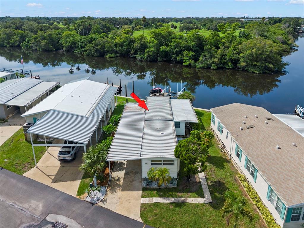An aerial view shows a mobile home with a metal roof and carport by water — 436 MOUNT OAK AVENUE NE UNIT 747, ST PETERSBURG, FL