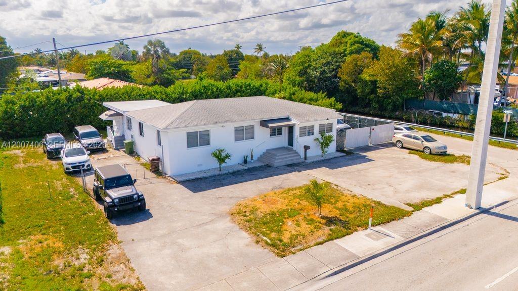 An aerial view of a white, single-story house with a large paved parking area — 5290 Palm Ave, Hialeah FL 33012, HIALEAH, FL