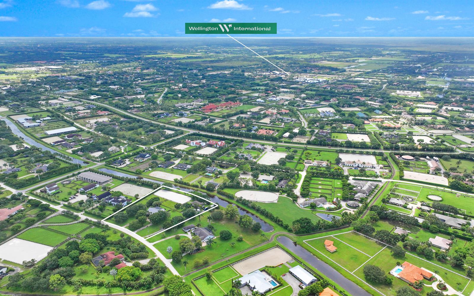 An aerial view shows a residential neighborhood with equestrian properties, green spaces, and a canal — 14564 Rolling Rock Place, Wellington FL 33414, WELLINGTON, FL
