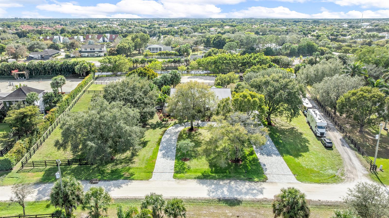 An aerial view shows a house with a circular driveway, mature trees, and horse fencing — 14564 Rolling Rock Place, Wellington FL 33414, WELLINGTON, FL
