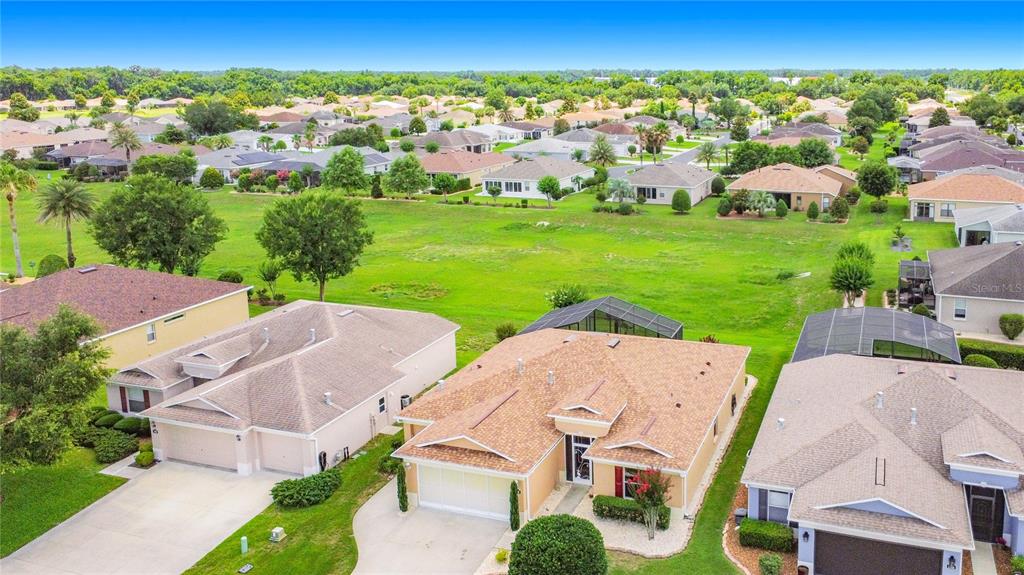 An aerial view shows a suburban neighborhood with several single-family homes and a large grassy field — 1508 SW 161ST PLACE, OCALA, FL
