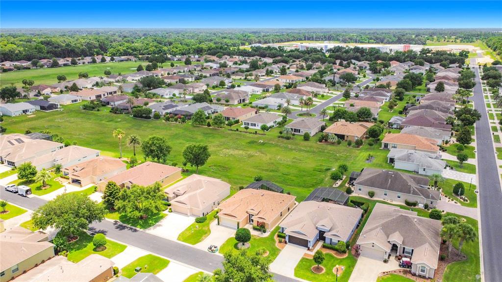 An aerial view shows a suburban neighborhood with single-family homes surrounding a large grassy field — 1508 SW 161ST PLACE, OCALA, FL