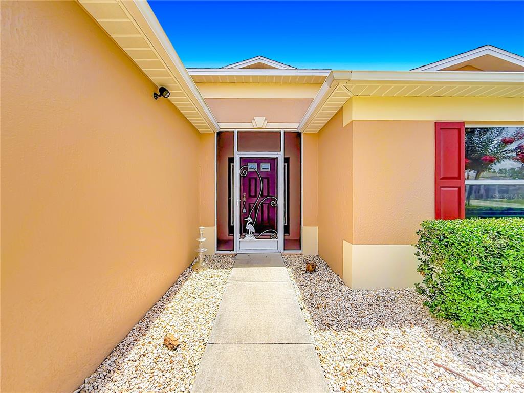 A concrete walkway leads to a front door with a decorative metal security screen — 1508 SW 161ST PLACE, OCALA, FL