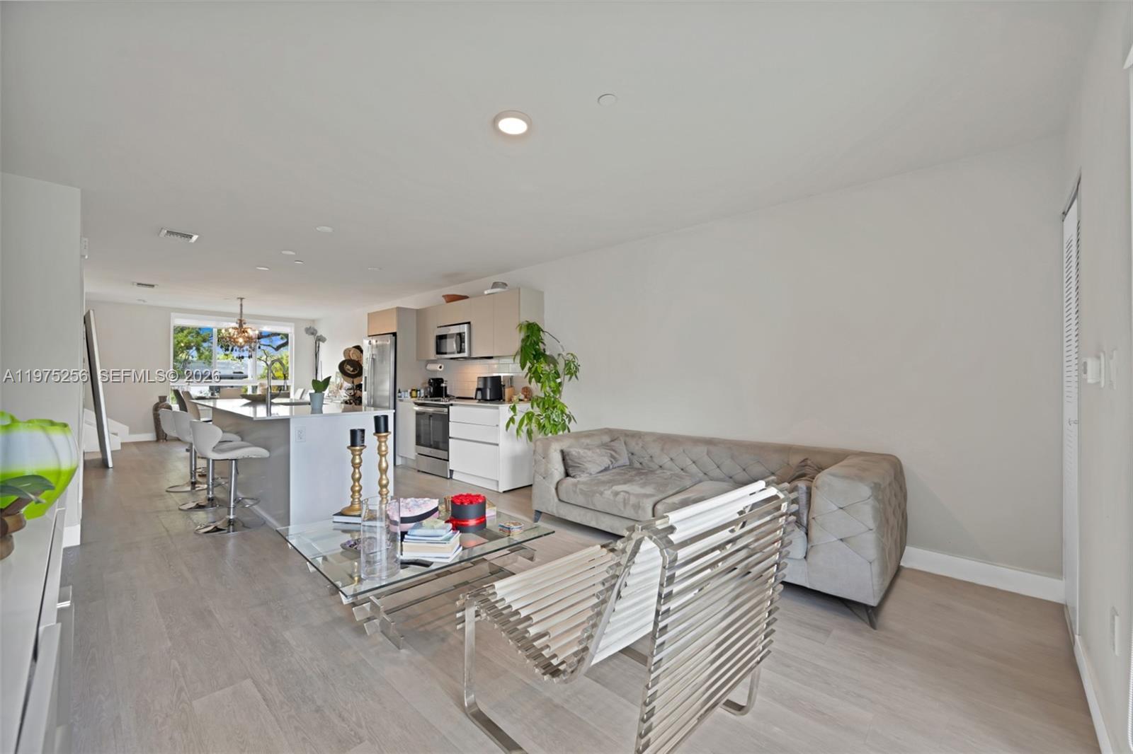 An open-concept living room and kitchen feature light wood flooring and a gray sofa — 2535 NE 193rd St # 3209, Miami FL 33180, MIAMI, FL