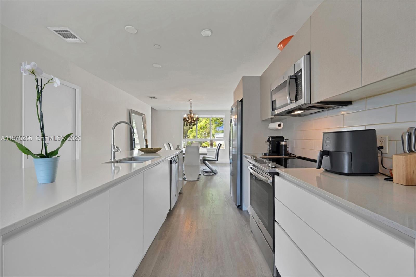 A modern galley kitchen features white cabinetry, quartz countertops, and stainless steel appliances — 2535 NE 193rd St # 3209, Miami FL 33180, MIAMI, FL
