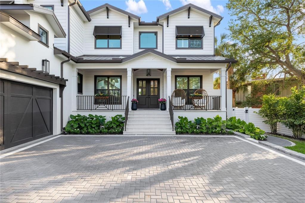 A two-story white house with a dark roof, black window frames, and a paved driveway — 4634 HIGEL AVENUE, SARASOTA, FL