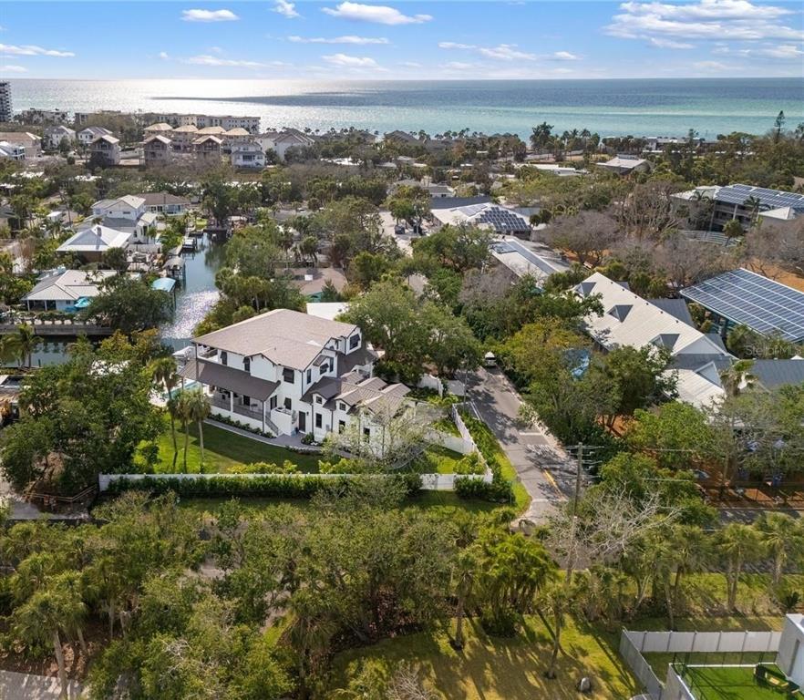 An aerial view shows a multi-story house with a white exterior near a coastal waterway — 4634 HIGEL AVENUE, SARASOTA, FL