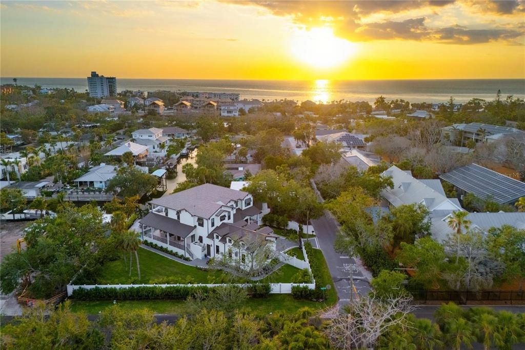 An aerial view shows a white house with a dark roof surrounded by lush greenery — 4634 HIGEL AVENUE, SARASOTA, FL