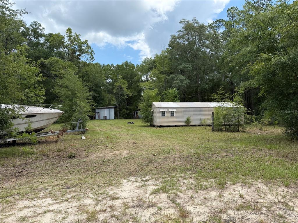 A boat on a trailer sits on a grassy lot near a mobile home — 9730 NE STATE ROAD 24, ARCHER, FL