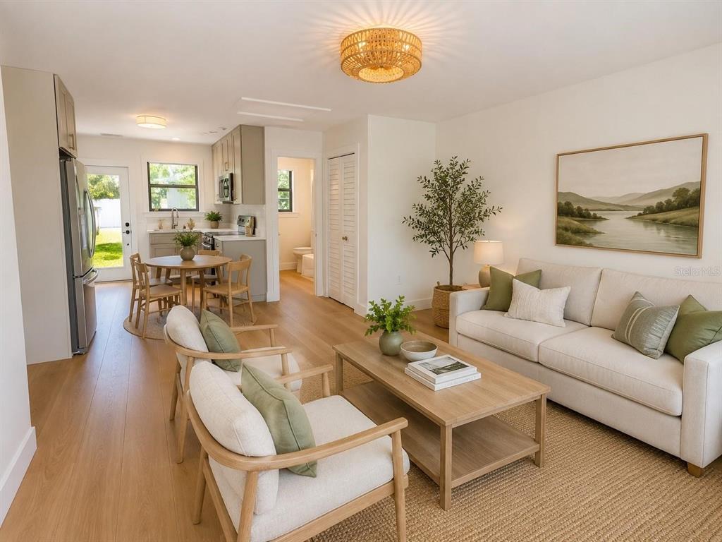A bright, open-concept living room and kitchen area with light wood flooring and neutral decor — 3219 E DE BAZAN AVENUE, ST PETERSBURG, FL