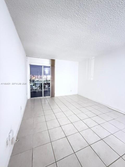 An empty room with white walls, a popcorn ceiling, and light-colored tile flooring — 4550 NW 9th St # 812E, Miami FL 33126, MIAMI, FL