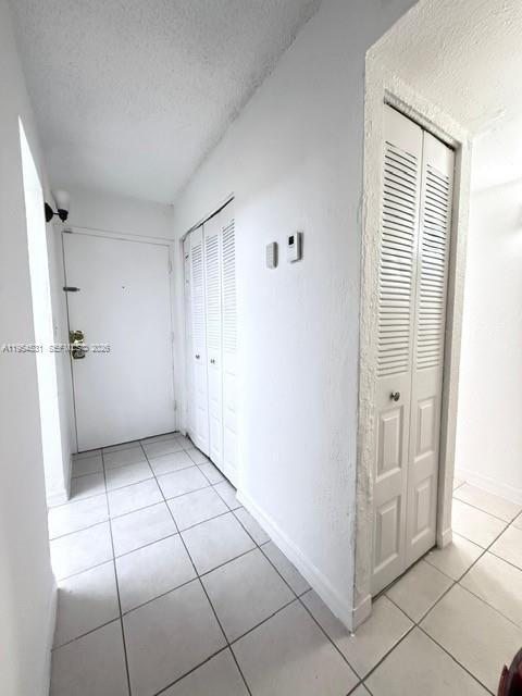 A white-walled entryway features tiled floors, a front door, and two sets of louvered closet doors — 4550 NW 9th St # 812E, Miami FL 33126, MIAMI, FL