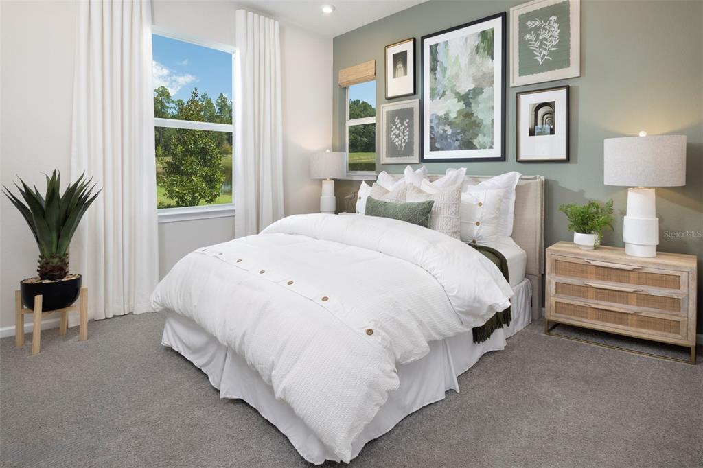A bedroom features a bed with white bedding, a sage green accent wall, and a window — 18468 GREEN GARDEN COURT, VENICE, FL