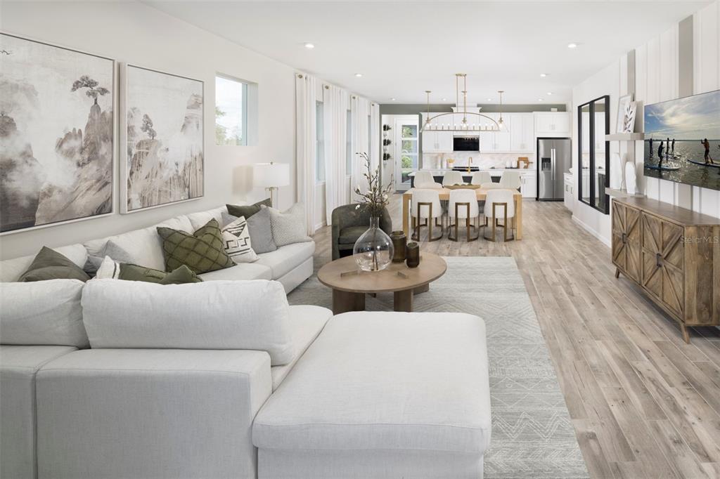 A bright, open-concept living and dining area features white cabinetry, light wood floors, and furniture — 18468 GREEN GARDEN COURT, VENICE, FL