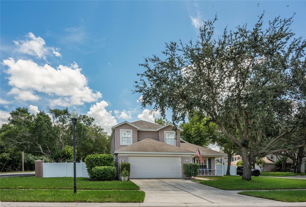 A two-story suburban house with a tan exterior, a two-car garage, and a large tree — 9609 FREDERICKSBURG ROAD, TAMPA, FL