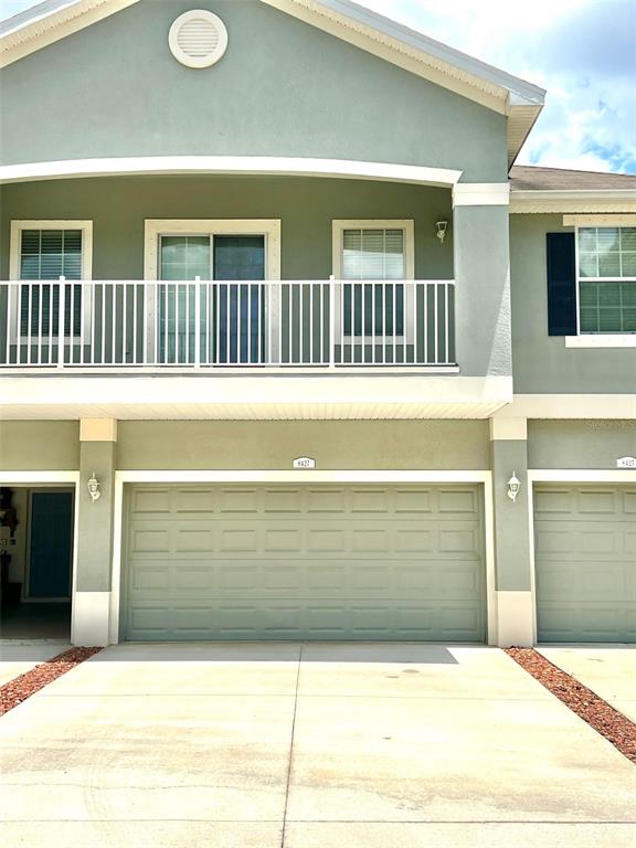 A two-story building features a light green exterior, a balcony, and two garage doors — 8427 BLUE ROCK DRIVE, NEW PORT RICHEY, FL