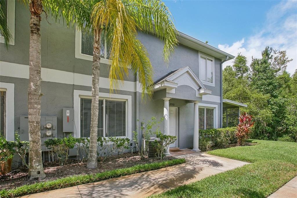 A two-story gray townhouse with a covered entryway, white columns, and a palm tree — 18181 PARADISE POINT DRIVE, TAMPA, FL