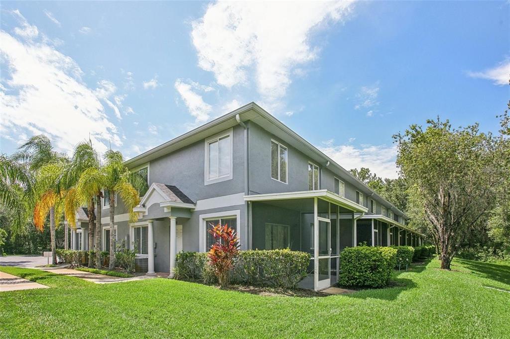 A two-story gray apartment building features screened-in patios and palm trees on a sunny day — 18181 PARADISE POINT DRIVE, TAMPA, FL