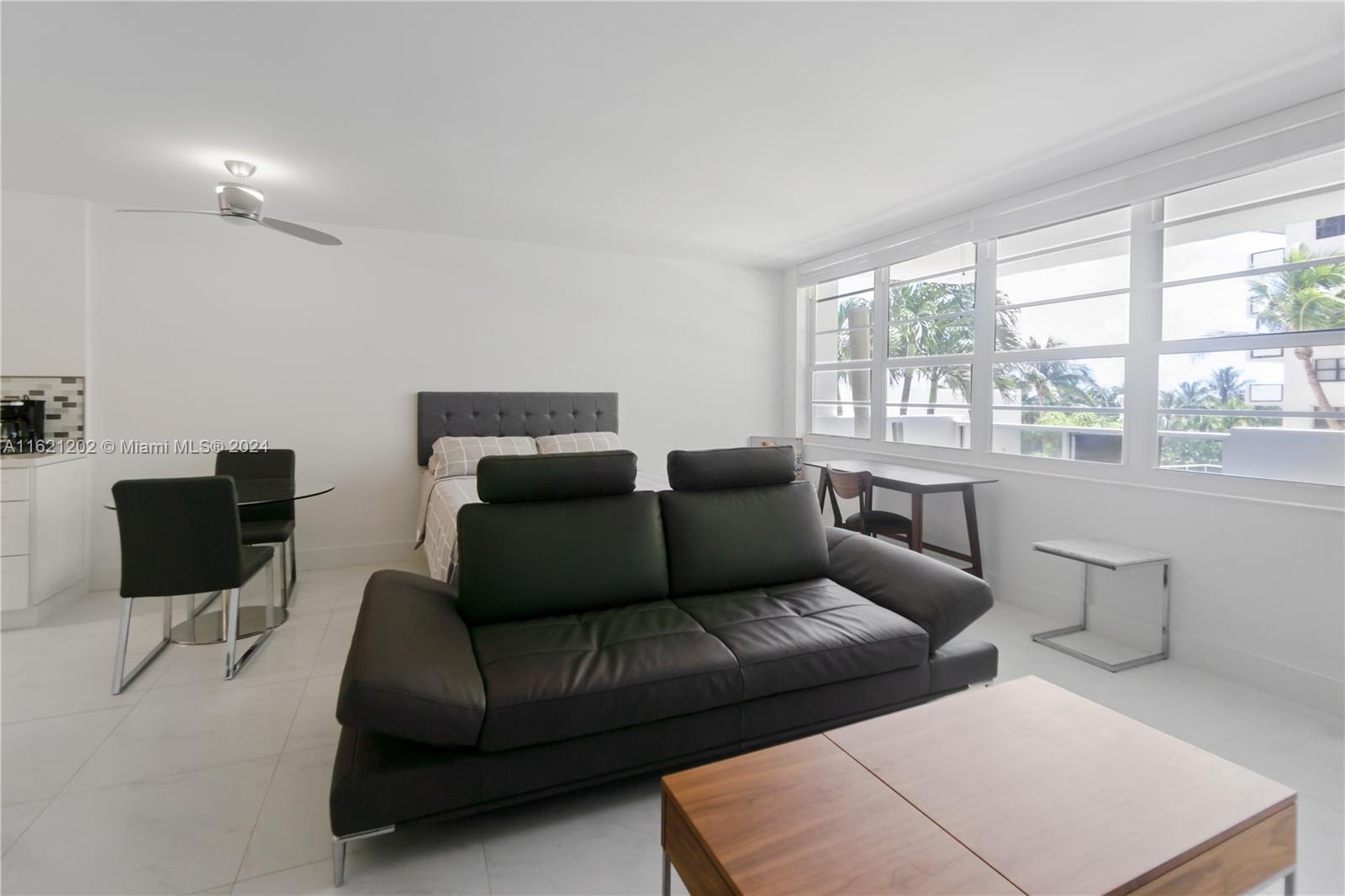 A studio apartment features a bed, a black sofa, a dining set, and large windows — 100 Lincoln Rd # 436, Miami Beach FL 33139, MIAMI BEACH, FL