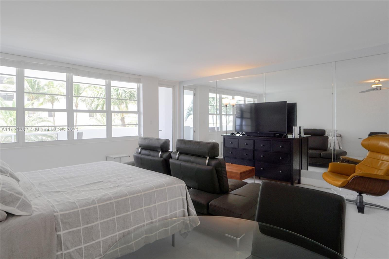 A bedroom features a bed, dark leather seating, a dresser with a television, and mirrored walls — 100 Lincoln Rd # 436, Miami Beach FL 33139, MIAMI BEACH, FL