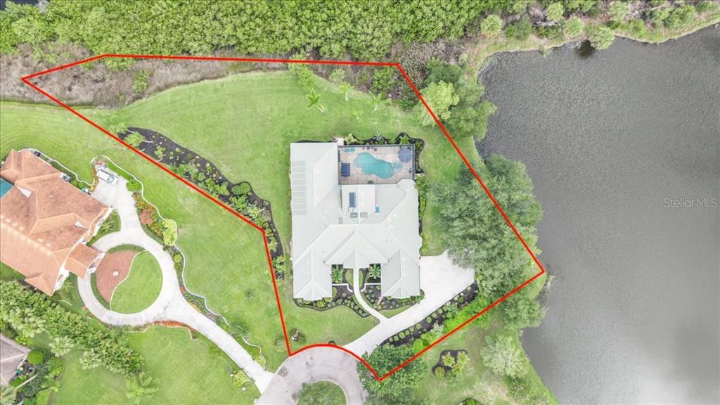 An aerial view shows a house with a pool on a lot bordering a lake — 3001 RIVERSHORE LANE, PORT CHARLOTTE, FL