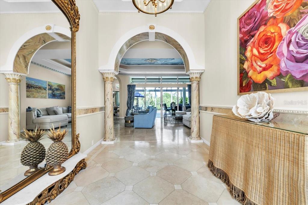 A tiled foyer features an arched entryway, decorative columns, a large mirror, and floral artwork — 3001 RIVERSHORE LANE, PORT CHARLOTTE, FL
