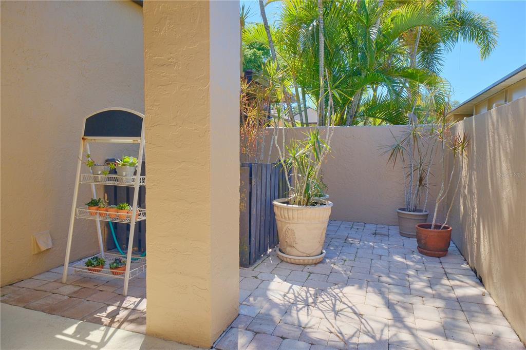 A paved outdoor patio features a tiered plant stand and several potted plants — 5257 MYRTLE WAY UNIT 29, SARASOTA, FL