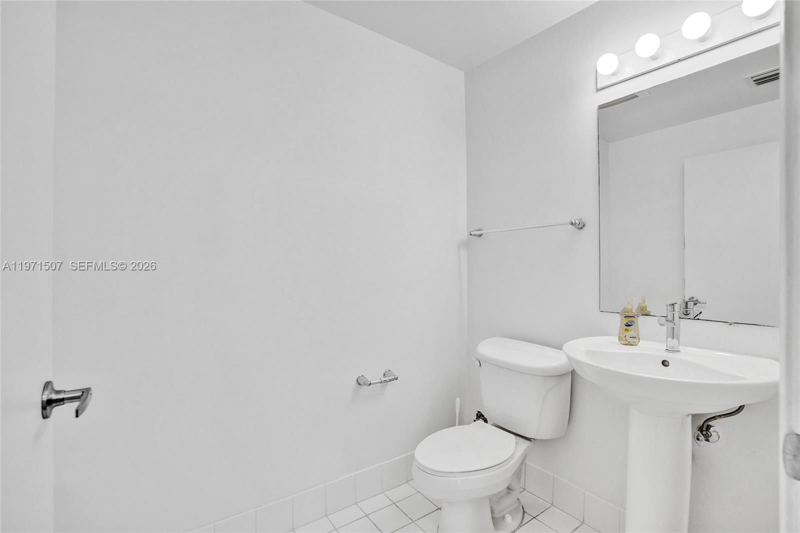 A small bathroom features a white pedestal sink, a toilet, and a wall-mounted mirror — 601 NE 36th St # 1908, Miami FL 33137, MIAMI, FL