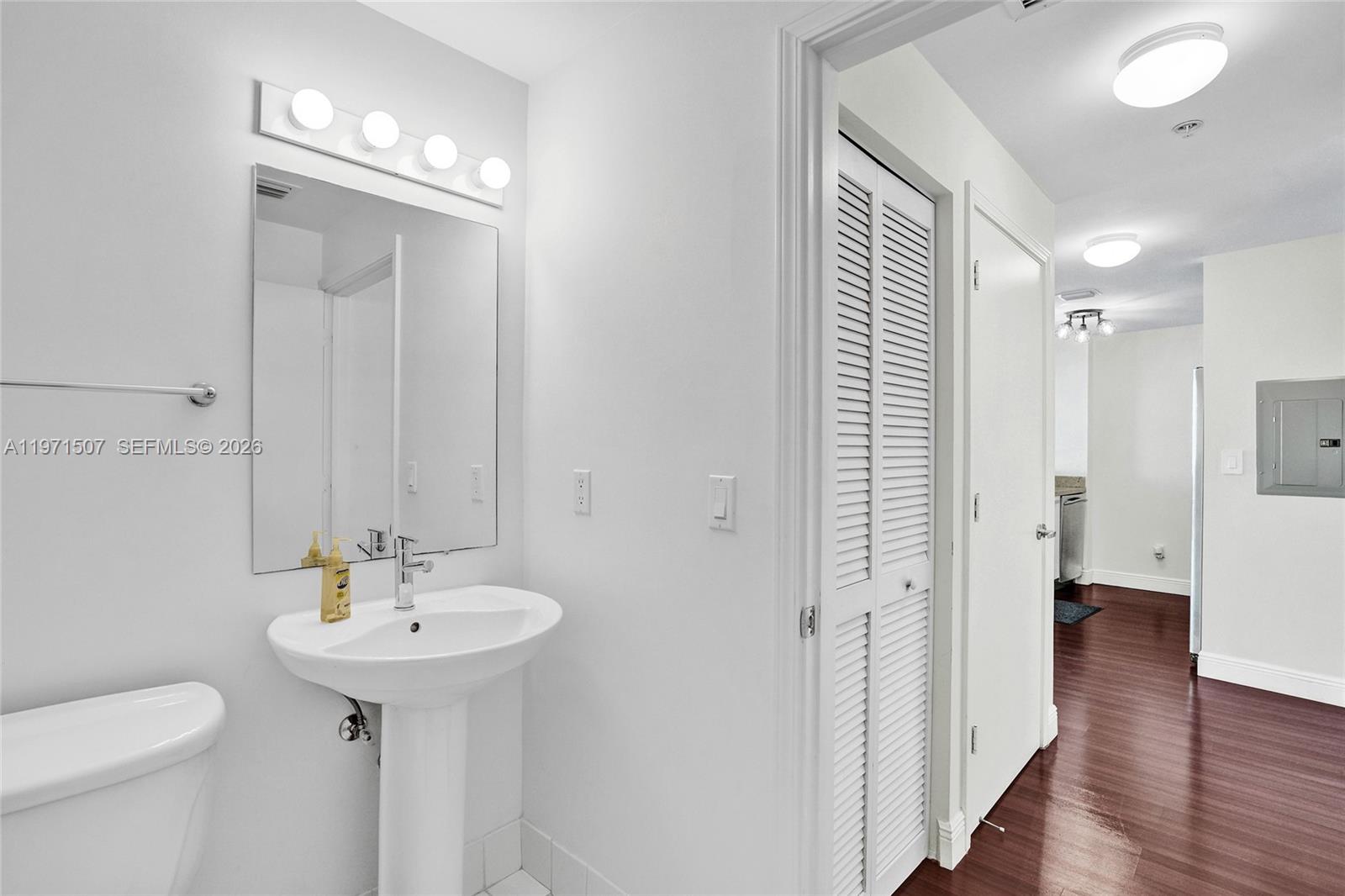 A white pedestal sink and toilet are in a bathroom with a louvered closet door — 601 NE 36th St # 1908, Miami FL 33137, MIAMI, FL
